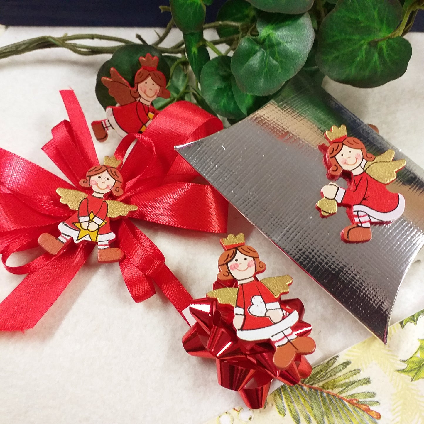 angeli su fiocco coccarda bustina argento angioletti rossi natalizi piastrine applicazioni legnetti uso segnaposto cenone capodanno san silvestro natale packaging chiudipacco confezione regalo