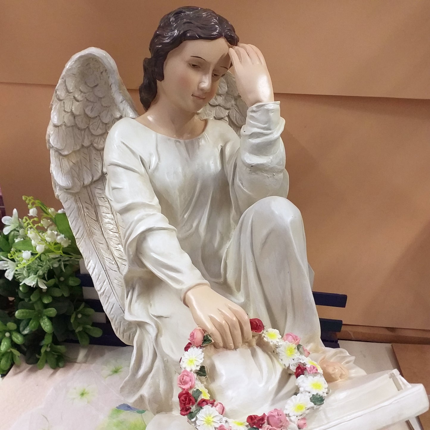 visione frontale grande statua angelo custode in preghiera con composizioni fiori Natale ad uso decorazioni all'esterno in giardino arte funeraria cimitero lapidi tombe cappelle