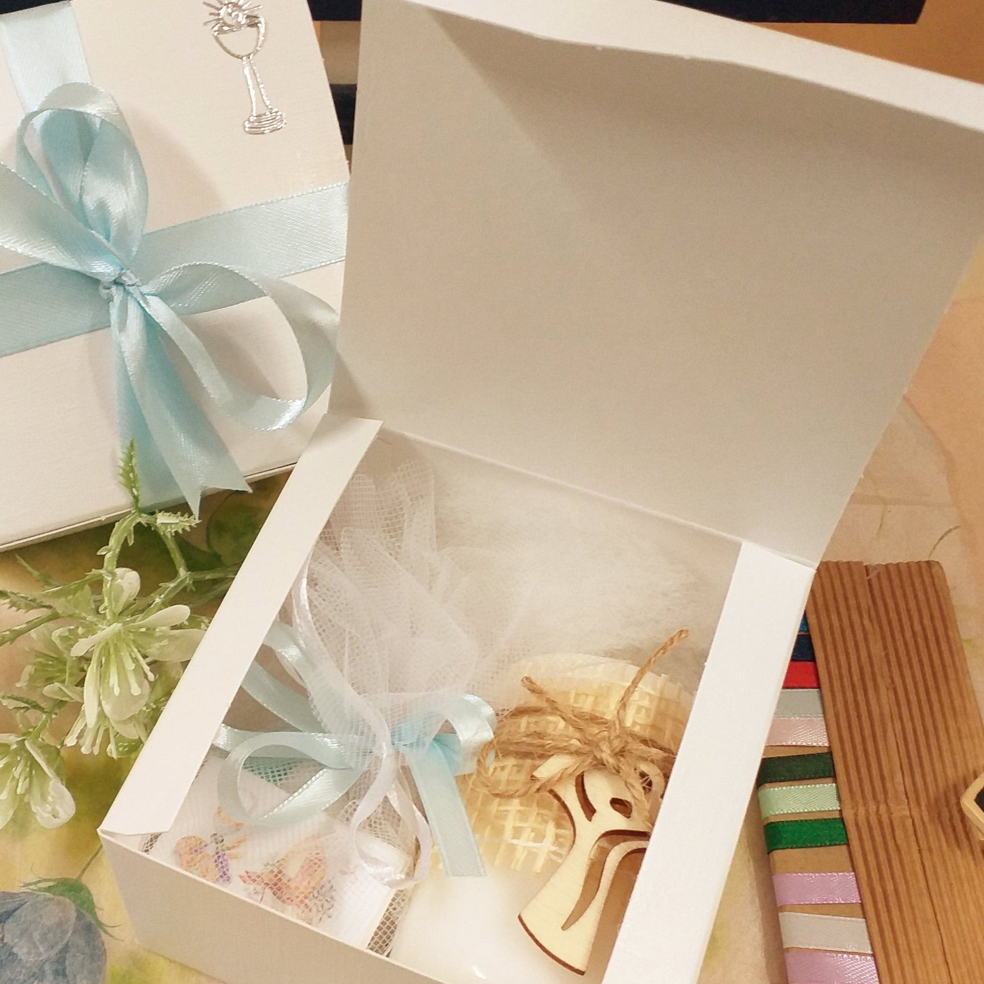dall'alto scatole bianche basse quadrate coperchio bordo all'interno uso packaging confezionamento oggetti bomboniere fai da te candela croce tau sacchettino confetti