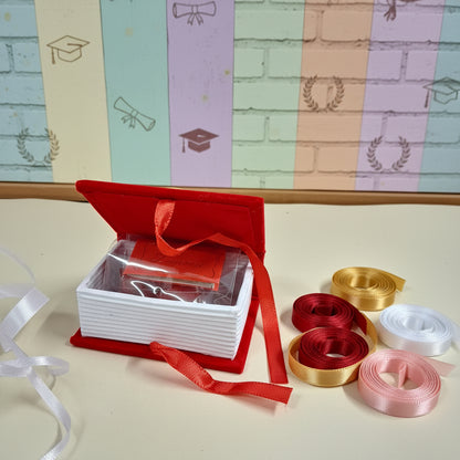 scatolina aperta originale portaconfetti bomboniera laurea segnaposto festa confezionata confetti bigliettino personalizzabile con colore nastrino raso, allestimento tocco cappello e nappina muro con simboli grafici pergamena corona alloro 