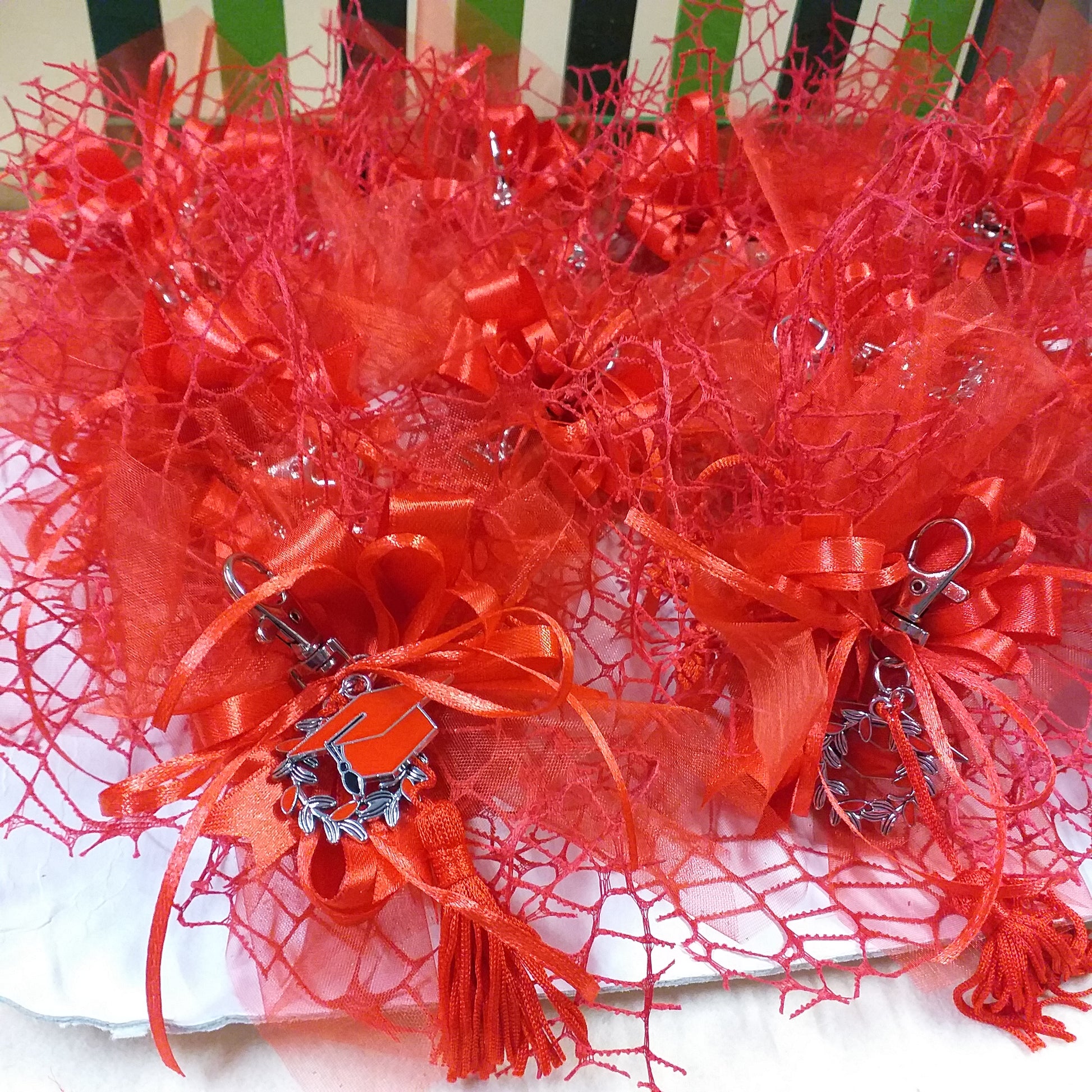 vassoio della confettata con confezionamento packaging composizione nastro bigliettino bomboniera confetti portachiavi laurea di metallo corona d'alloro tocco cappello nappina rossa decorativa