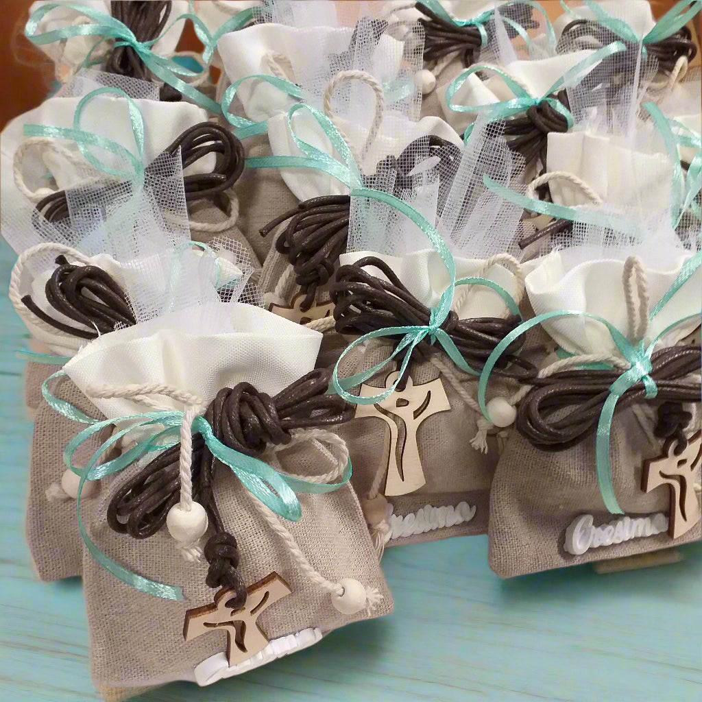 dall'alto allestimento shop bomboniere portaconfetti sacchetti juta-cotone con applicazione gessetto scritta Cresima confezionato confetti bigliettino simboli  collana corda marrone Croce Tau legno francescana perle