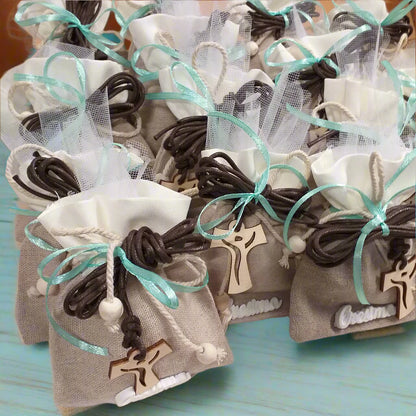 dall'alto allestimento shop bomboniere portaconfetti sacchetti juta-cotone con applicazione gessetto scritta Cresima confezionato confetti bigliettino simboli  collana corda marrone Croce Tau legno francescana perle