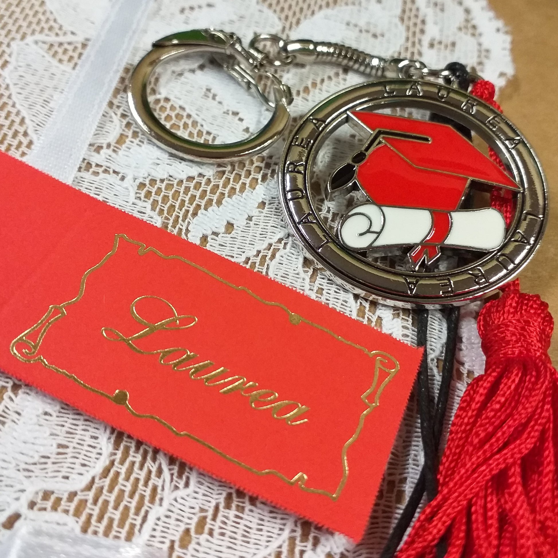 bigliettino e portachiavi tocco cappello laurea rosso ciondolo smaltato pergamena bianca nappina rossa scritta laurea sul tondo metallo zama della bomboniera gancio catenina
