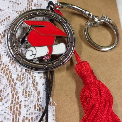primo piano portachiavi tocco cappello laurea rosso ciondolo smaltato pergamena bianca nappina rossa scritta laurea sul tondo metallo zama della bomboniera gancio catenina