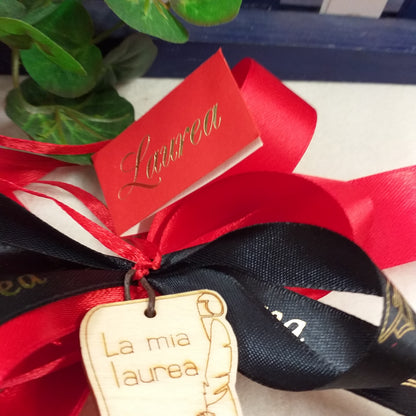 primo piano bigliettino e simbolo fiocco coccarda segnaposto fai da te o confezionato packaging rosso-nero ciondolo green legno pirografato la mia laurea calamaio pergamena