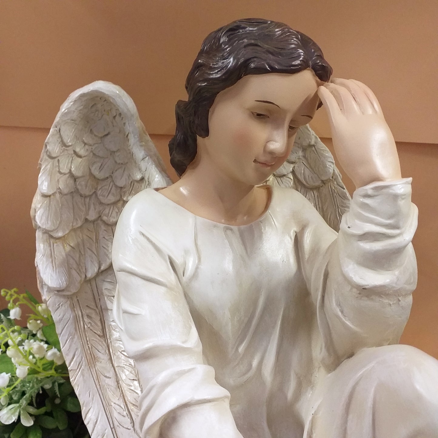 primo piano grande statua angelo custode in preghiera con composizioni fiori Natale ad uso decorazioni all'esterno in giardino arte funeraria cimitero lapidi tombe cappelle